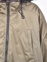 Campera gris con capucha con borde de piel sintética, cierre frontal con cremallera, bolsillos laterales con solapa y bolsillo con cremallera en la manga.