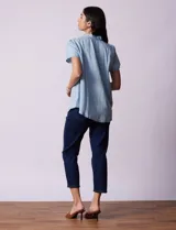 Camisa celeste de tencel con cuello con solapa, escote en V y abertura central con botones. Delantera con detalle en punto smock.