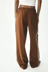 Pantalón marrón de tiro alto con cintura elástica, bolsillos delanteros y detalle de banda lateral blanca a contraste.