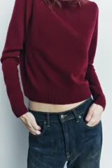 Jersey rojo de punto liso confeccionado en 100% lana. Tiene cuello redondo, manga larga y acabados en rib.