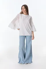 Blusa blanca de algodón con mangas largas acampanadas con volados.