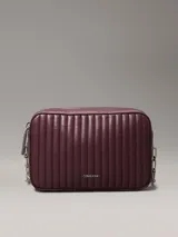 Cartera bandolera Calvin Klein color borgoña con diseño acolchado vertical. Tiene correa de cadena plateada, cierre superior con cremallera y logo metálico en el frente.