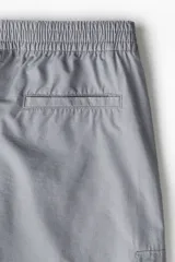 Pantalón cargo gris de sarga de mezcla de algodón, con elástico fruncido en la cintura y cierre con botón a presión. Cuenta con bolsillos al bies con cierre, bolsillo insertado en una pierna, bolsillos con solapa en las piernas y bolsillos insertados atrás. Corte estándar para una silueta clásica y cómoda.