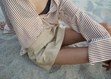 Camisa de manga larga con cuello camisero y cierre frontal de botones. Diseño recto con estampado de rayas verticales en tonos rojizos y beige.