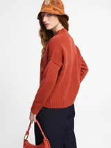 Sweater de tejido de punto color marrón, con escote en v y mangas de sisa caída.