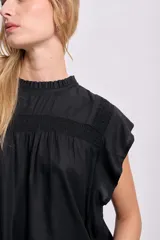 Blusa negra sin mangas con cuello redondo y detalle de volados en los hombros.