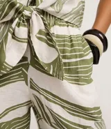 Pantalón tipo pantacourt confeccionado en viscosa con estampado de follaje verde sobre fondo blanco, con cintura elástica y diseño de pierna ancha y corta.