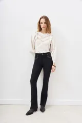 Pantalón de jean negro de corte flare con detalle de tachas metálicas en los bolsillos delanteros.