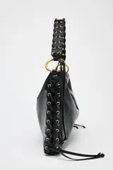 Bolso de hombro alargado color negro, con detalle de pasados metálicos en los laterales y asa trenzada. Tiene doble bolsillo interior con cremallera y cierre mediante botón imantado.