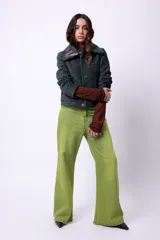 Campera corta de poliéster texturizado color verde oscuro, con cuello camisero, cierre frontal con botones a presión, bolsillos delanteros y forro interior. Incluye pins decorativos.