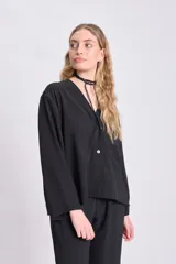 Blusa negra de manga larga con cuello en V y cierre con botones.