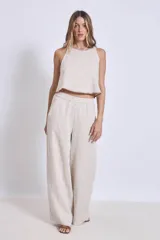 Conjunto de lino color beige, compuesto por un top sin mangas con cuello halter y un pantalón palazzo de tiro alto con cintura elastizada.