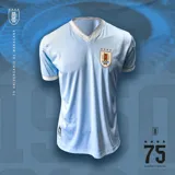 Camiseta de fútbol celeste con cuello en V y mangas cortas con ribete blanco. Escudo de Uruguay bordado en el pecho.