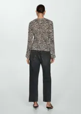 Blusa de tejido fluido color crema con estampado animal print negro, cuello en V y mangas largas abullonadas.