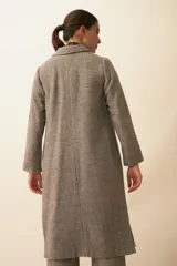 Tapado largo con cuello solapa y corte recto, color gris claro. Tiene cierre frontal con botones ocultos, tajos laterales y bolsillos escondidos en el corte lateral. Está forrado y confeccionado en lana fina sin teñir, diseñada exclusivamente por Don Baez. Hecho 100% en Uruguay.