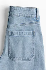 Jean celeste de denim de algodón con corte wide leg, tiro alto, largo cropped y bolsillos de parche traseros.