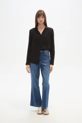 Camisa de viscosa color crema con finas rayas verticales negras, corte al cuerpo, cuello camisa y dos bolsillos frontales con tapa. Posee botones frontales y mangas largas con puño.