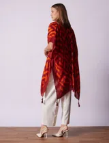 Kimono tejido con estampado geométrico en blanco y negro, ruedo con borlas y composición 100% poliéster.