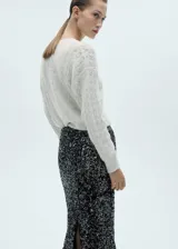 Sweater color crudo de punto grueso con detalle de lurex, cuello redondo y manga larga.