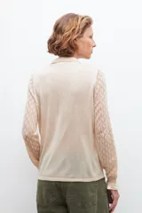 Cardigan de tejido ligero color beige melange con mangas caladas y cierre frontal.