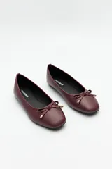 Balerinas negras de símil cuero texturizado con aplique de moña y detalles metálicos.