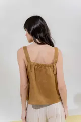 Top de lino color beige con breteles anchos y silueta cuadrada. Presenta una pieza aplicada en la delantera con detalle de vainillas en los laterales y frunce en el escote de la espalda.