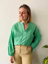 Blusa verde menta de corte holgado, con escote en V y detalle de puntilla en el escote y mangas largas con puños elásticos.