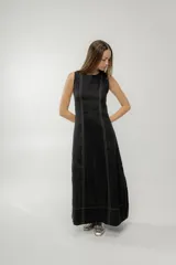 Vestido largo negro sin mangas, con cuello redondo y corte trapecio. Presenta costuras verticales con pespuntes en color crudo.