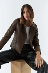 Campera marrón de cuero sintético, estilo motociclista, con cuello solapa, cierre asimétrico, bolsillos con cierre y detalles de costuras en los hombros y mangas.