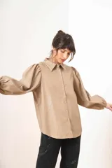 Camisa beige de efecto piel con cuello clásico, mangas largas abullonadas y cierre frontal con botones a tono.