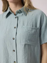 Camisa blanca de manga corta con cuello clásico y bolsillo en el pecho. Confeccionada en lino y viscosa.