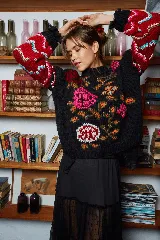 Sweater de lana tejido a mano color negro con bordado de flores rosas, naranjas y rojas. Tiene cuello redondo y mangas largas con puños ajustados.