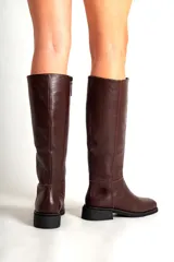 Botas de cuero de caña alta, con punta cuadrada y taco bajo. Disponibles en color bordó y negro.