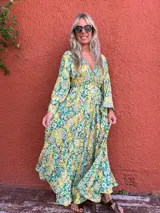 Vestido largo de seda con escote en V y mangas largas amplias. Presenta un estampado tipo cachemir o mandala en tonos verde, amarillo y blanco/crudo.