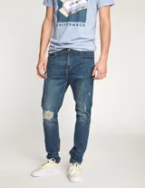 Pantalón de jean azul con roturas en las rodillas, corte slim fit.