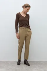 Pantalón negro de vestir, corte recto y tiro alto, con pliegues frontales y puños doblados. Se complementa con un cinturón fino negro con hebilla metálica en forma de símbolo.