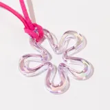 Collar con dije de flor transparente con efecto iridiscente y cordón fucsia.