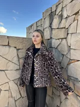 Chaqueta corta de gamulán sintético con estampado animal print, cuello solapa y cierre frontal con botones dorados.