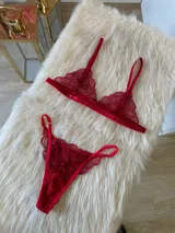 Conjunto de lencería rojo de encaje, compuesto por un bralette triangular con breteles regulables y una tanga regulable con corte media less y entrepierna de algodón.