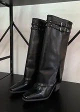 Botas de caña alta negras con hebillas plateadas y tachas.