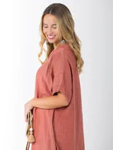 Vestido largo color ladrillo, de lino, corte amplio, mangas cortas, cuello bote y bolsillos laterales.