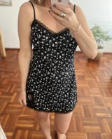 Camisolín corto negro con estampado floral blanco, breteles finos y detalles de encaje en escote y ruedo.