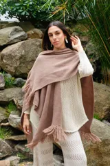 Ruana color crudo tejida a mano en punto arroz con lana merino. Presenta flecos en el borde inferior.