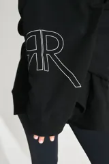 Buzo oversize negro de frisa esmerilada con capucha amplia, bolsillos laterales, terminaciones de puño y ruedo con rib, doble cordón con terminal termocontraíble y estampa serigrafiada en frente, manga y espalda con la palabra 'RENÉE'.