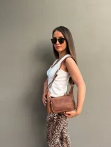 Cartera bandolera de cuero color marrón, con correa ajustable y bolsillo externo con cierre.