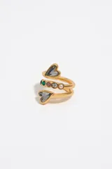 Anillo dorado con forma de espiral y corazones de cristal grises en los extremos. Incluye detalles de piedras de colores y logo grabado.