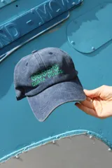 Gorro tipo jockey de tela denim azul gastado, con visera curva y bordado frontal en hilo verde que dice "COSTA DULCE".