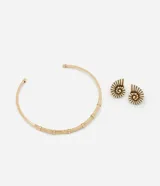 Conjunto de collar rígido dorado y aros tipo botón con forma de caracola en color crema y detalles dorados.