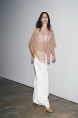 Blusa semitransparente color beige con bordados de hilo metalizado y abalorios. Tiene mangas cortas y cierre frontal con cordones.