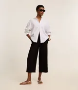 Pantalón tipo pantacourt negro, de corte sastre y tiro alto, con lazo ajustable en la cintura.